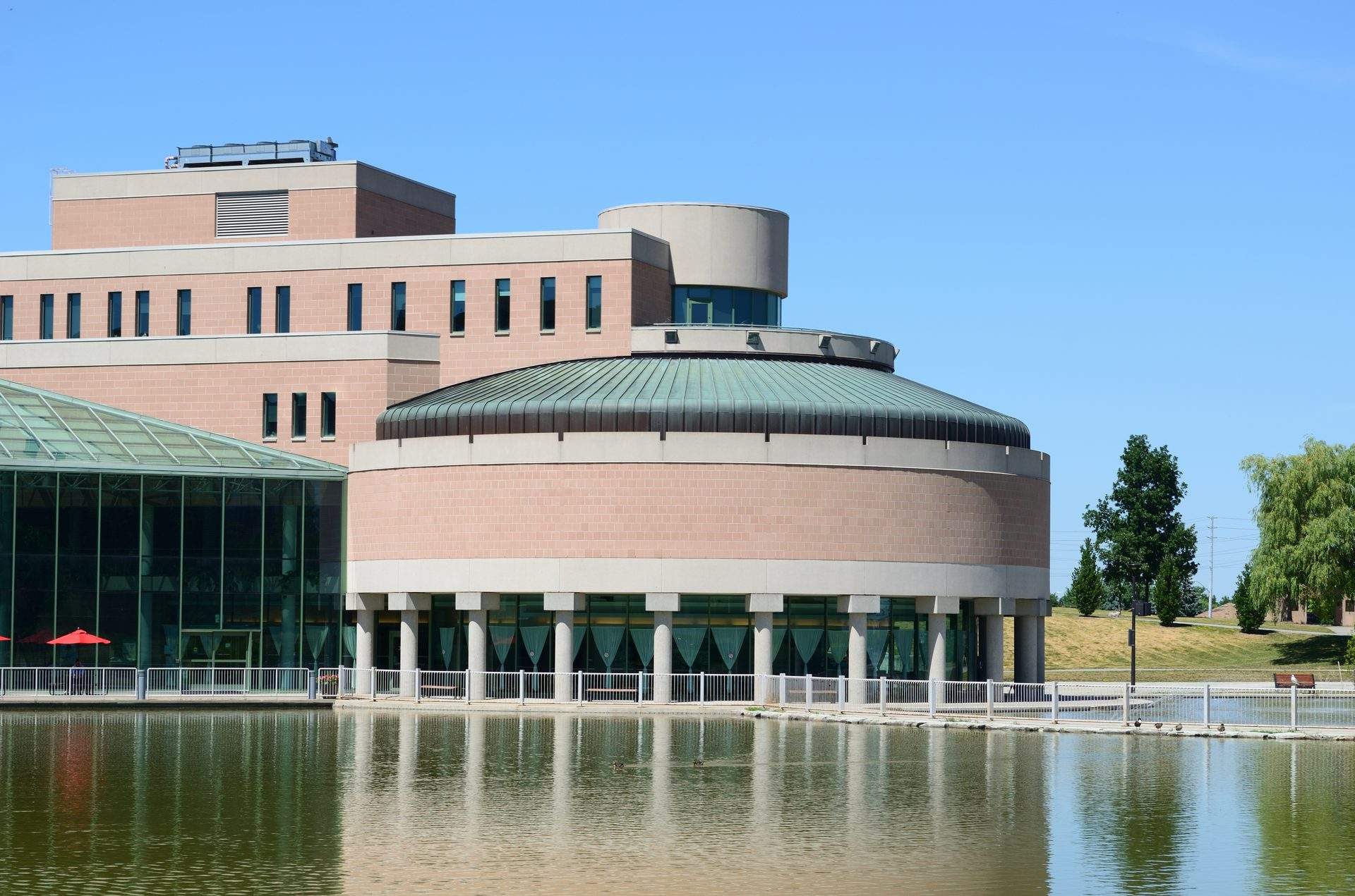 Markham Civic Centre building with modern circular architecture beside a reflective pond on a clear day.