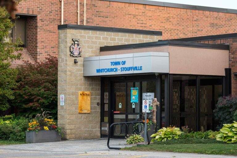 Entrance of the Town of Whitchurch-Stouffville municipal building with signage, brick exterior, and landscaped garden in front.