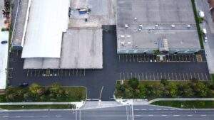 Aerial view of a commercial property with freshly sealcoated asphalt and newly painted parking lot lines, including accessible spaces and clear traffic markings.