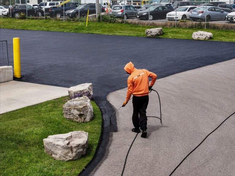 Action Paving technician applying protective commercial asphalt sealcoating to a parking lot edge in Bolton ON.