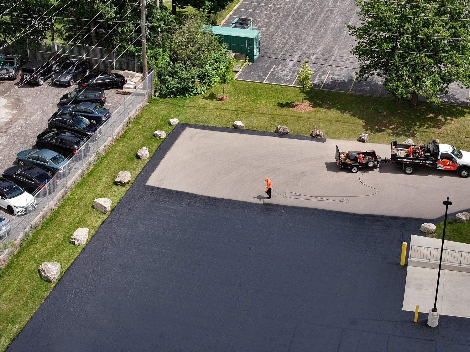Aerial view of Action Paving crew spraying sealcoat over a large commercial asphalt parking lot in Bolton Ontario.