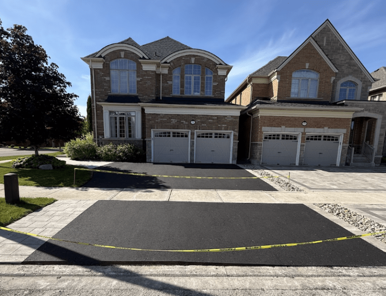 Newly paved blacktop residential driveway with caution tape curing in front of a modern home in Brampton ON.