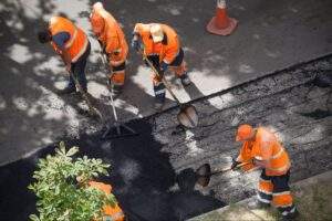 Construction crew performing asphalt pothole repairs and patch maintenance before winter freeze-thaw cycles